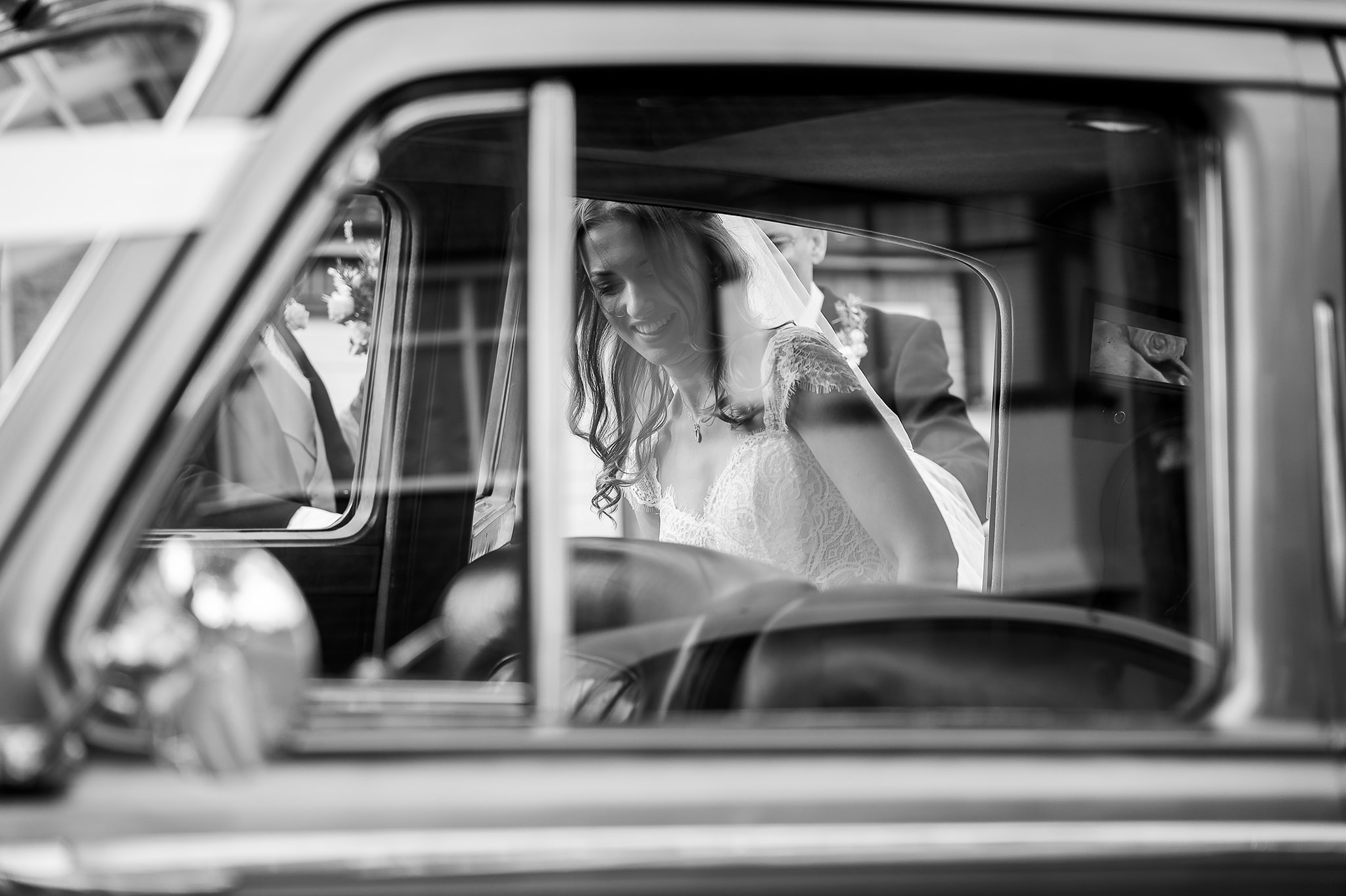 Artistic black and white candid close up photo of the beautiful bride entering her wedding vintage car
