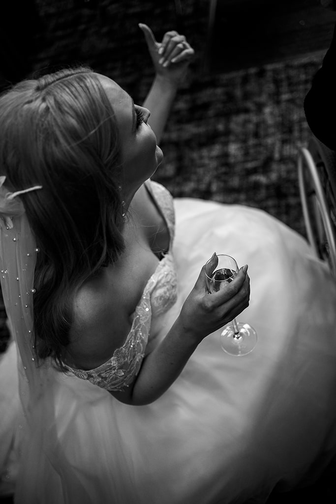 Black and white photo of bride holding a glass of champagne taken from above