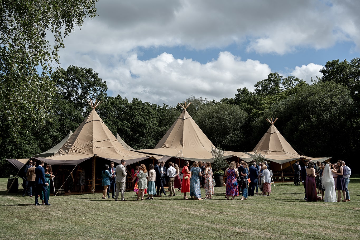 Huge wedding tipi tent set in garden grounds with guests mingling