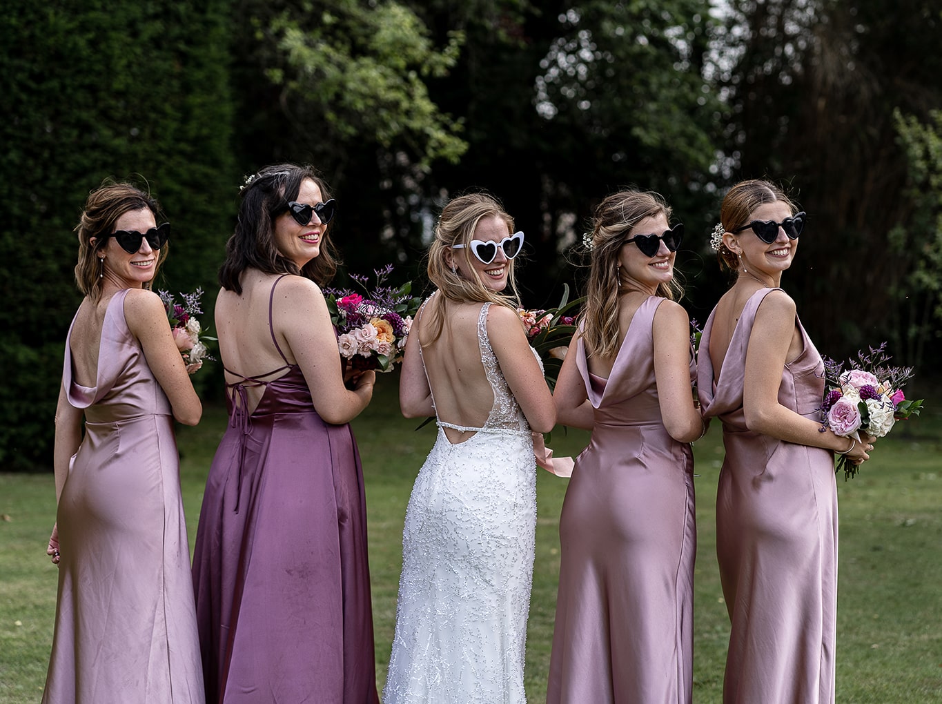 Happy bride and her bridesmaids wearing humorous heart-shaped sunglasses