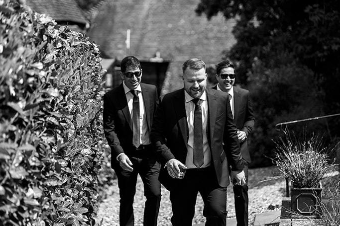 Candid black and white photo of groom and his groomsmen walking outside on their way to the wedding